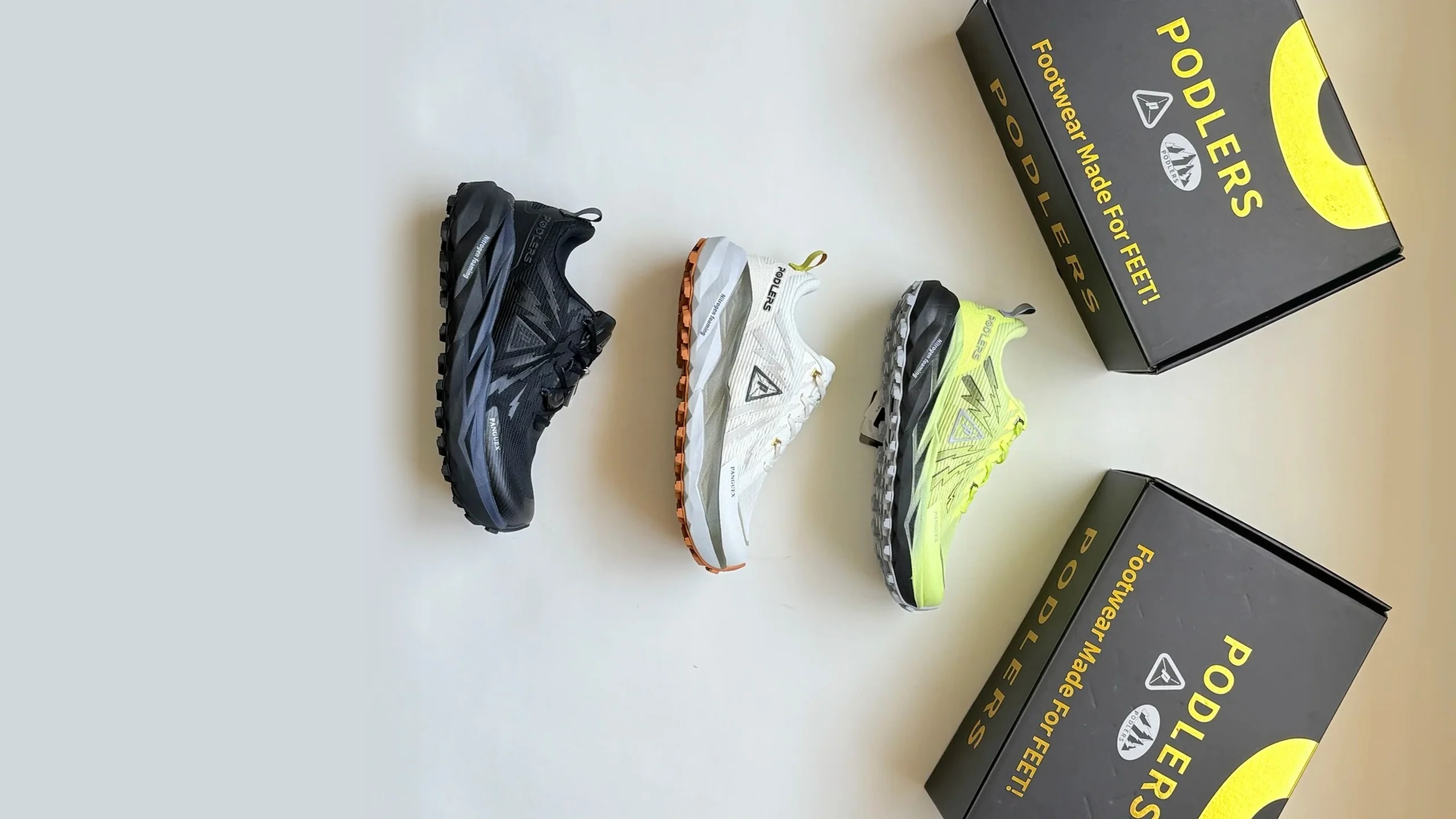 Three PODLERS trail shoes displayed beside branded boxes